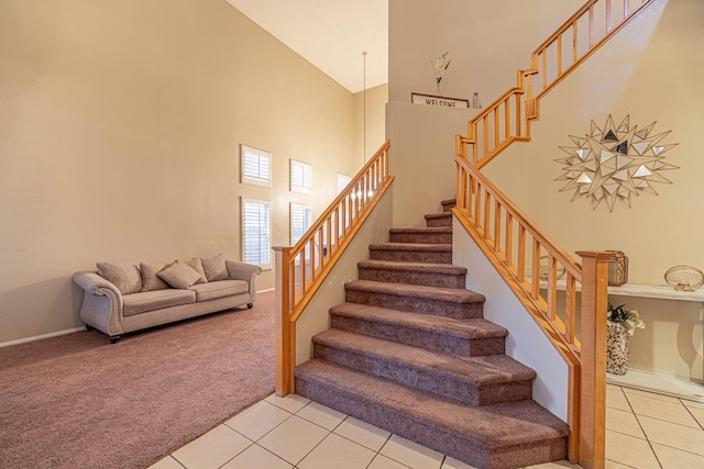 staircase featuring tile patterned flooring, a high ceiling, and carpet