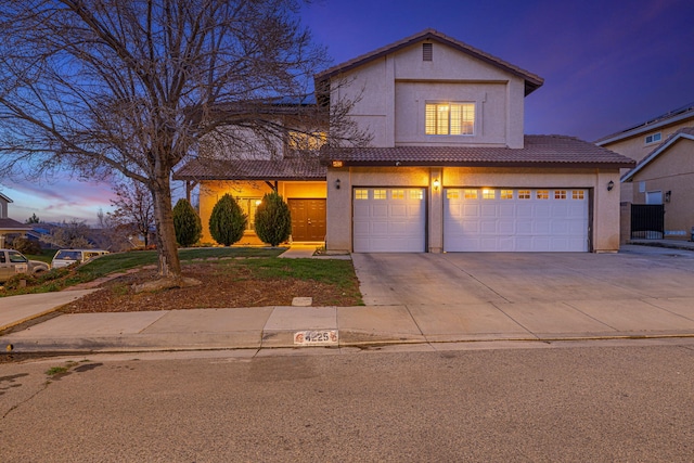 traditional-style house with a tiled roof, an attached garage, driveway, and stucco siding