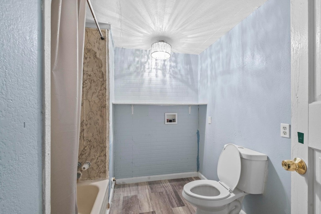 full bathroom with baseboards, toilet, and wood finished floors