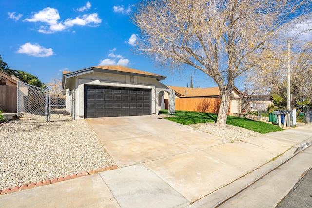 ranch-style house featuring a garage, concrete driveway, a gate, fence, and stucco siding