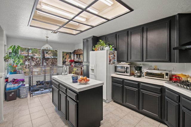 kitchen featuring a kitchen island, light tile patterned flooring, decorative light fixtures, and appliances with stainless steel finishes