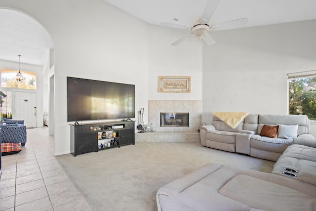 tiled living room with high vaulted ceiling, ceiling fan, and a tiled fireplace