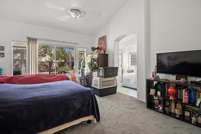 bedroom featuring ensuite bathroom, ceiling fan, light carpet, and vaulted ceiling