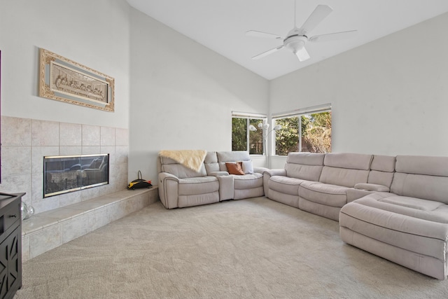 living room with ceiling fan, carpet floors, high vaulted ceiling, and a tiled fireplace