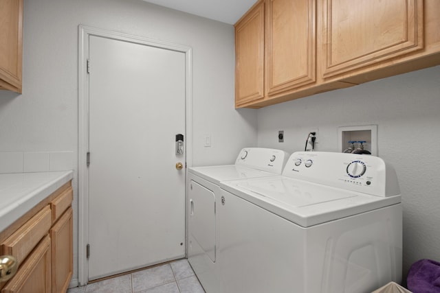 laundry area with cabinets, light tile patterned floors, and washing machine and clothes dryer