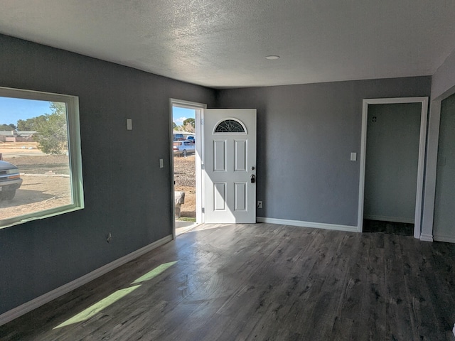 foyer entrance featuring baseboards, a textured ceiling, and wood finished floors