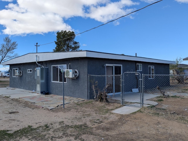 rear view of property featuring stucco siding, a gate, fence, and ac unit