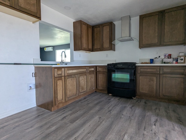 kitchen with light countertops, black range with electric stovetop, wood finished floors, a sink, and wall chimney range hood