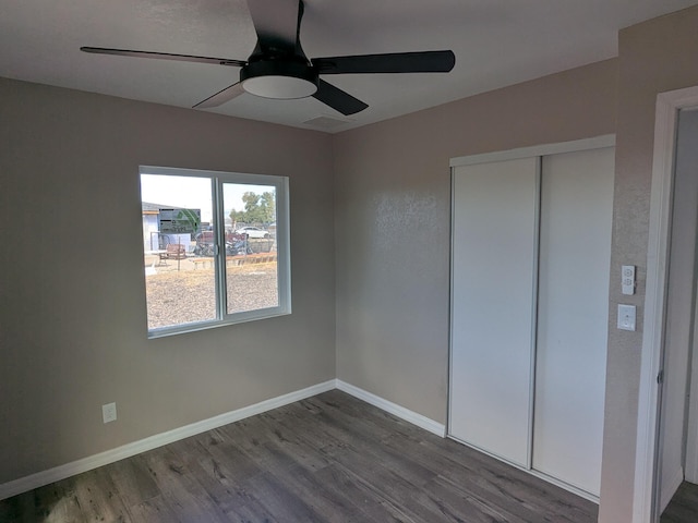 unfurnished bedroom with baseboards, ceiling fan, wood finished floors, and a closet