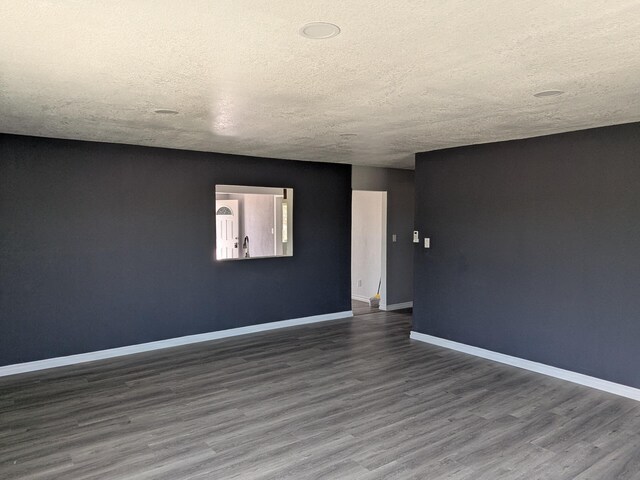 spare room featuring baseboards, a textured ceiling, and wood finished floors
