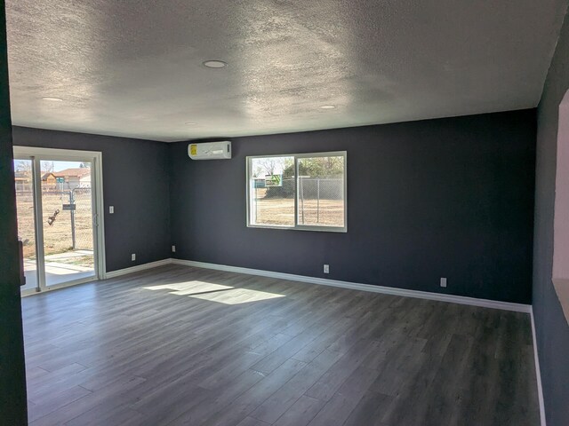 unfurnished room featuring dark wood-type flooring, baseboards, an AC wall unit, and a wealth of natural light