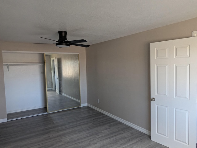 unfurnished bedroom featuring a closet, wood finished floors, a textured ceiling, baseboards, and ceiling fan