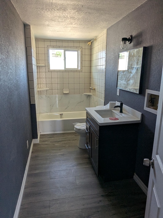 full bathroom with a textured ceiling, a textured wall, toilet, and wood finished floors