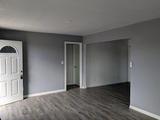 unfurnished room with baseboards and dark wood-type flooring