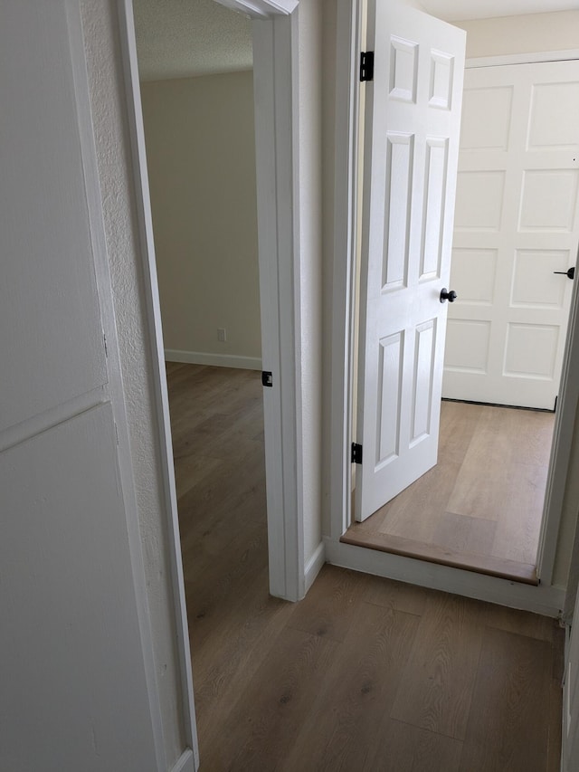 hallway featuring baseboards and wood finished floors
