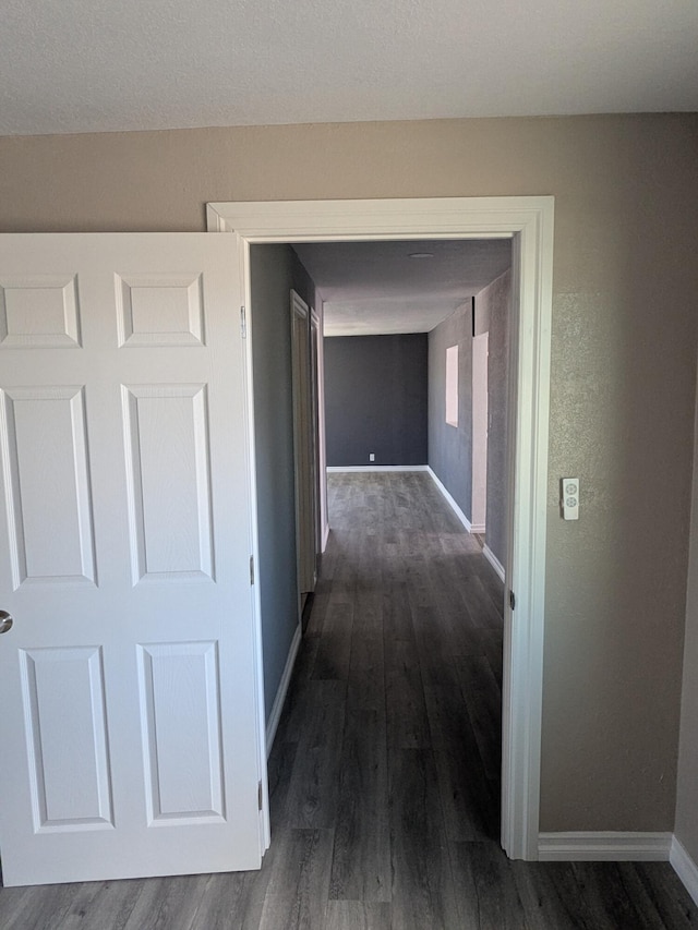 hall with dark wood-type flooring and baseboards