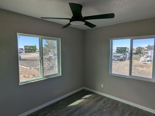 unfurnished room with dark wood finished floors, baseboards, a ceiling fan, and a healthy amount of sunlight