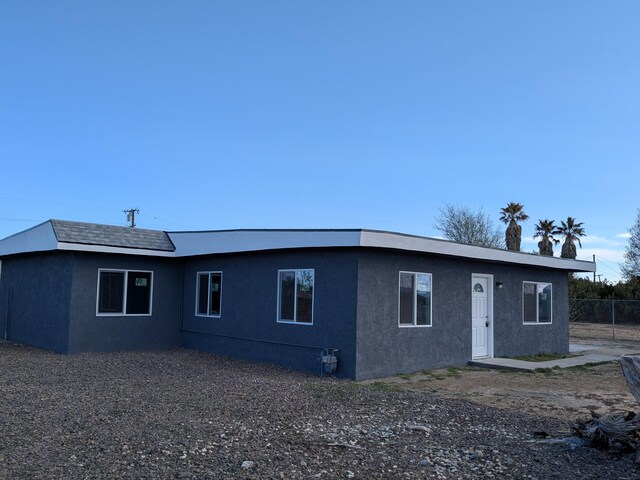 view of front facade featuring stucco siding and fence