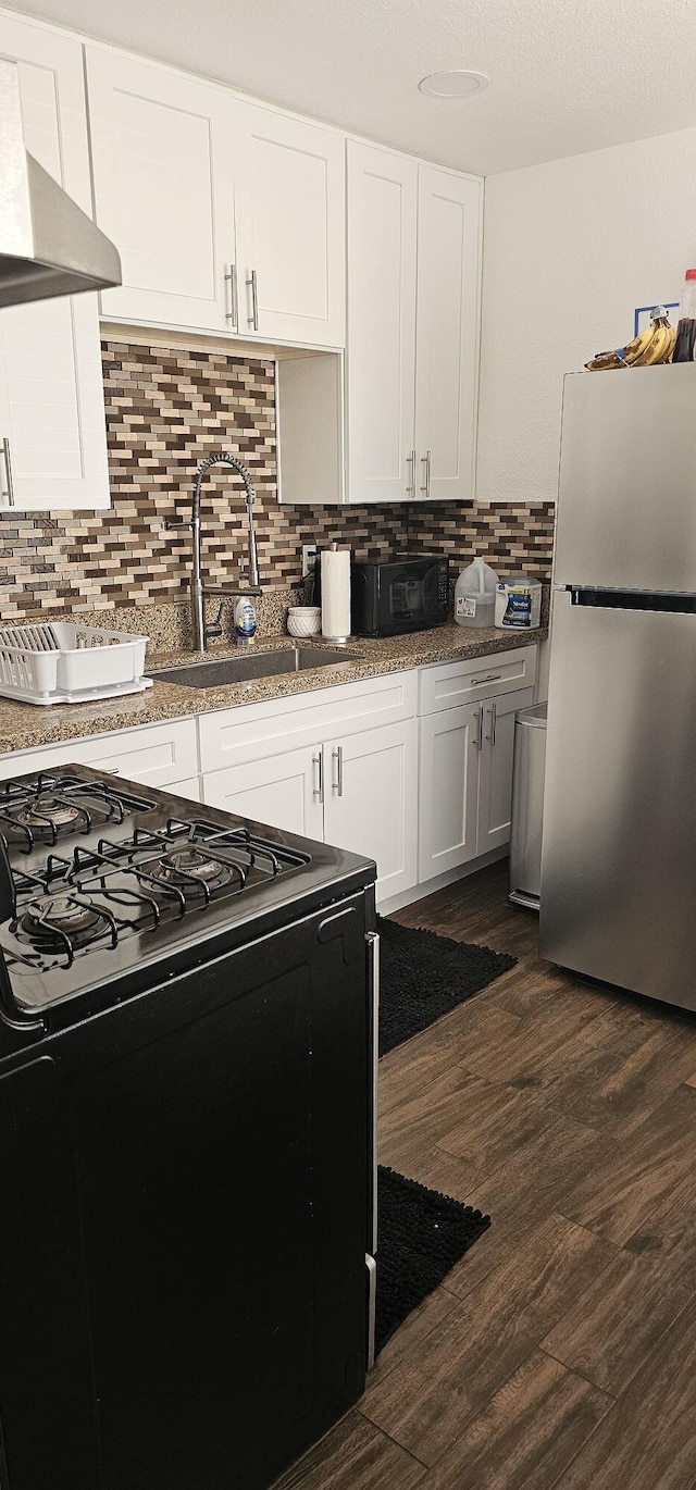 kitchen featuring white cabinetry, dark hardwood / wood-style flooring, black appliances, and wall chimney range hood