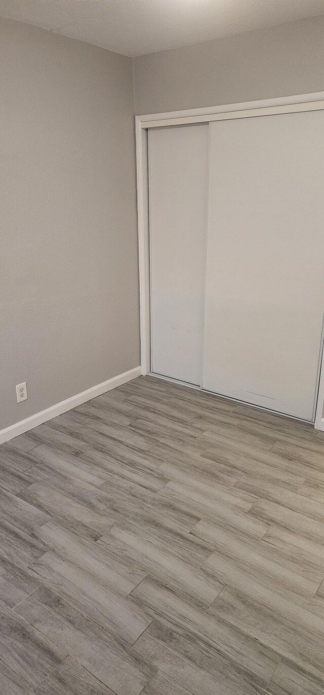 unfurnished bedroom with light wood-type flooring and a closet