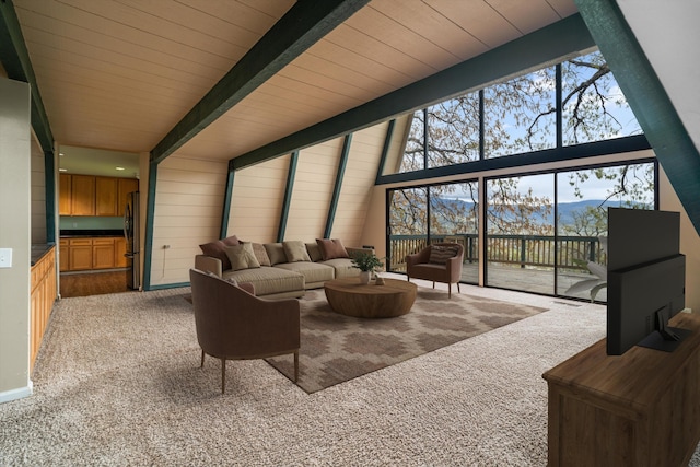 carpeted living area with beamed ceiling
