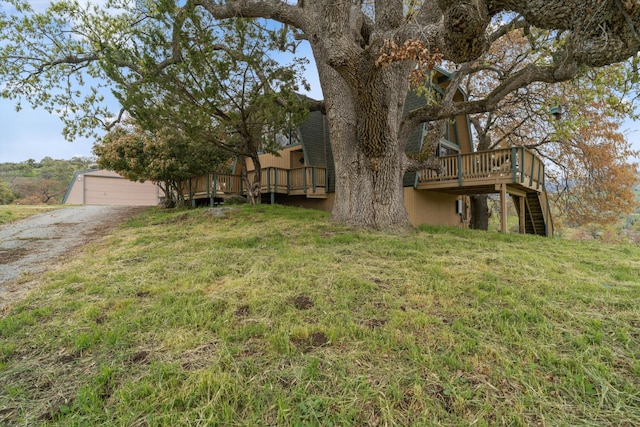view of yard featuring a detached garage, a wooden deck, an outbuilding, and stairway
