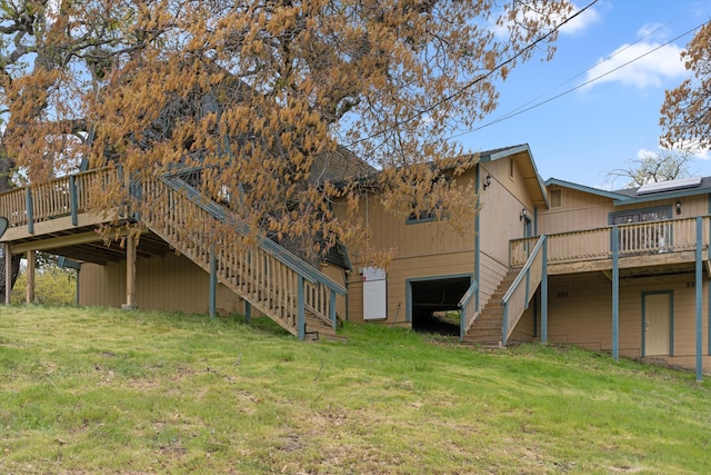 back of property with a lawn, a deck, and stairway