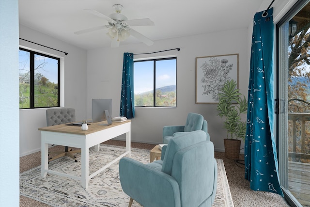 carpeted home office featuring baseboards, plenty of natural light, and ceiling fan