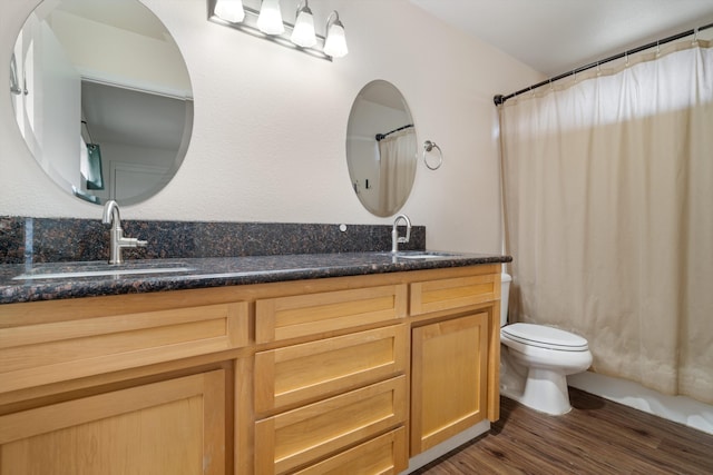 bathroom featuring a sink, double vanity, toilet, and wood finished floors