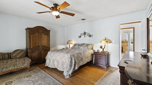 bedroom with a textured ceiling, visible vents, a ceiling fan, and light wood-type flooring