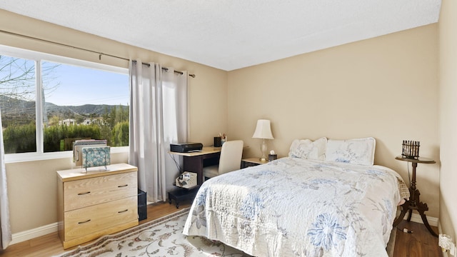 bedroom with baseboards, a mountain view, and wood finished floors