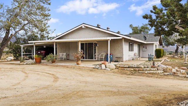 view of front of home featuring an attached carport, stucco siding, and a patio area