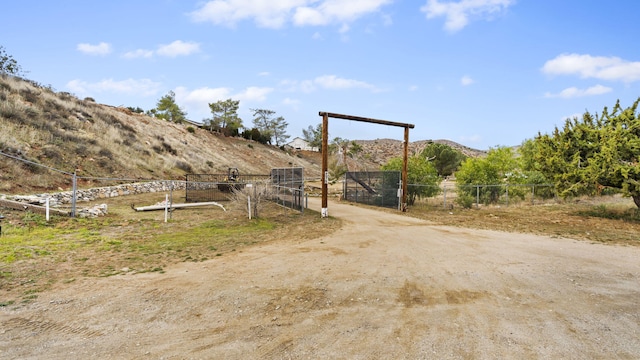 view of street with a gated entry, driveway, a mountain view, and a rural view