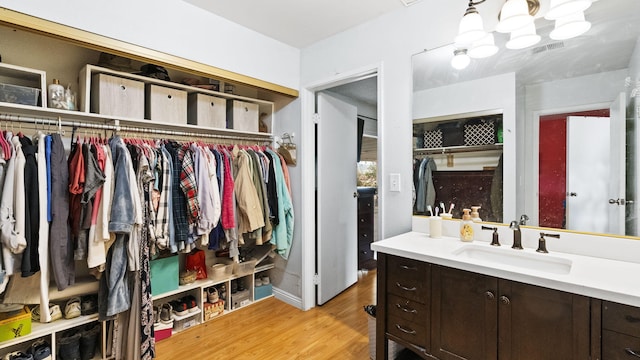 walk in closet featuring light wood-style flooring, a sink, and visible vents