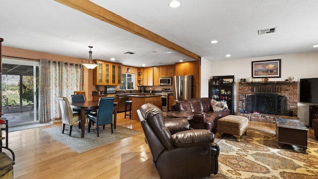 living area with visible vents, light wood-style flooring, recessed lighting, and a brick fireplace
