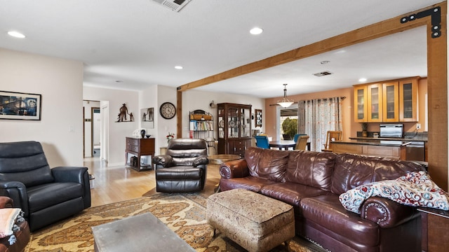 living area featuring recessed lighting, light wood-style floors, beamed ceiling, and visible vents