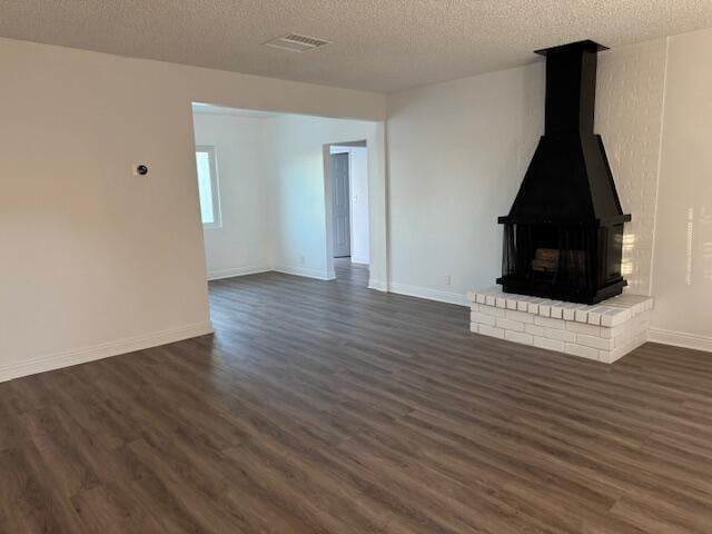 unfurnished living room featuring dark hardwood / wood-style floors, a wood stove, and a textured ceiling