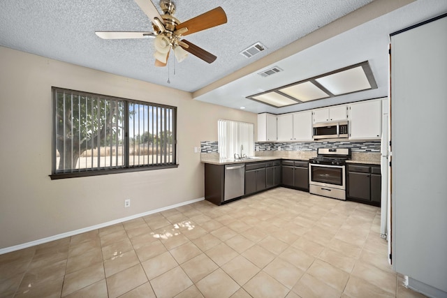 kitchen featuring backsplash, stainless steel appliances, sink, white cabinetry, and light tile patterned flooring