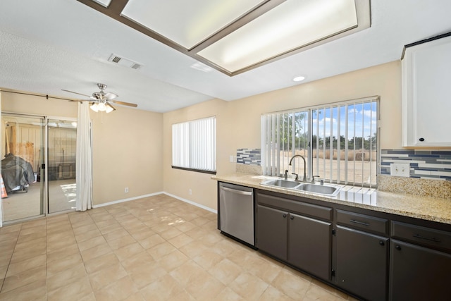 kitchen featuring sink, stainless steel dishwasher, decorative backsplash, ceiling fan, and light stone counters