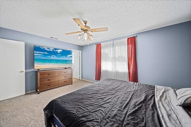 carpeted bedroom featuring ceiling fan and a textured ceiling