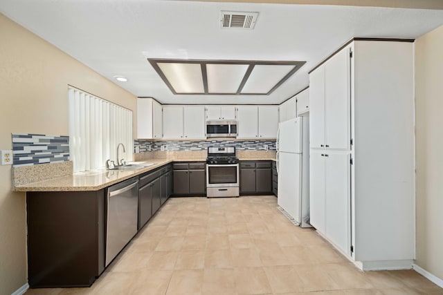 kitchen with tasteful backsplash, light stone counters, stainless steel appliances, sink, and white cabinets