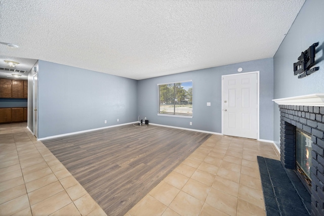 tiled living room with a textured ceiling and a brick fireplace