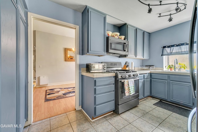 3628 Marilynn St, Lancaster, CA 93536 - kitchen with appliances with stainless steel finishes, light tile patterned floors, tile countertops, and open shelves