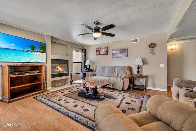 3628 Marilynn St, Lancaster, CA 93536 - living area with wood finished floors, a textured ceiling, a ceiling fan, and a glass covered fireplace