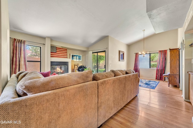 3628 Marilynn St, Lancaster, CA 93536 - living area with lofted ceiling, healthy amount of natural light, light wood-type flooring, a chandelier, and a glass covered fireplace
