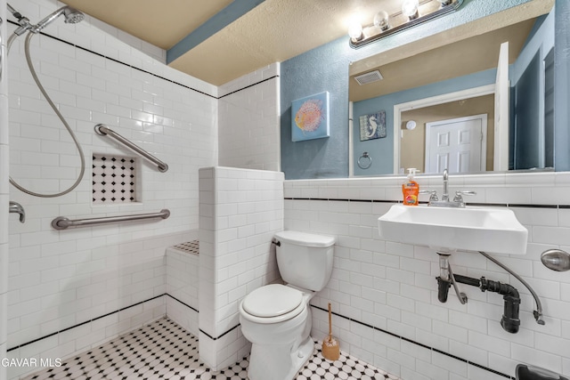 3628 Marilynn St, Lancaster, CA 93536 - bathroom featuring tiled shower, tile walls, wainscoting, and tile patterned flooring
