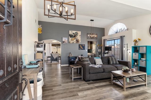 living room with high vaulted ceiling, hardwood / wood-style floors, and an inviting chandelier