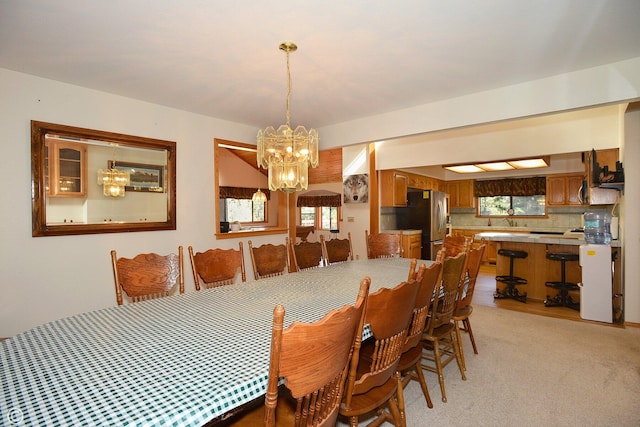 dining area with light carpet and an inviting chandelier