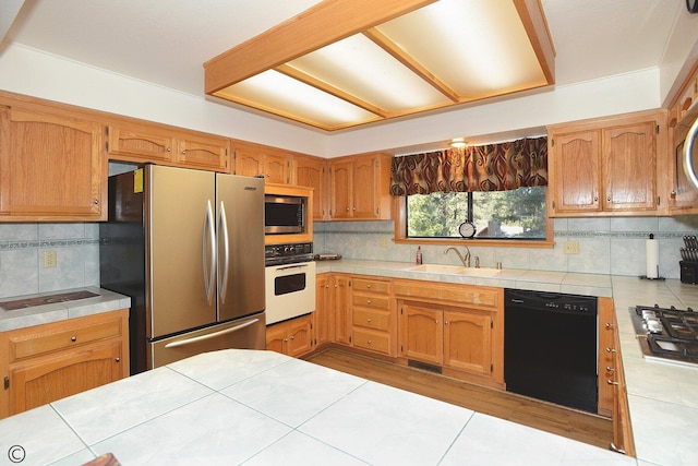 kitchen with tile countertops, decorative backsplash, sink, and stainless steel appliances