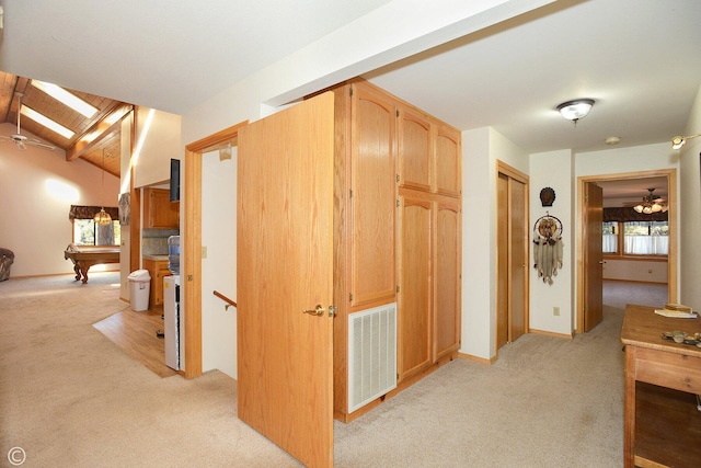 hall featuring lofted ceiling with beams and light colored carpet